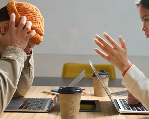 An office scenario illustrating a challenging interaction between colleagues. One person, visibly frustrated, holds their head in their hands, while the other person gestures emphatically. This scene underscores the importance of effective communication and strategies for managing difficult people in the workplace. The FutureForward logo is displayed in the corner, indicating the training context.