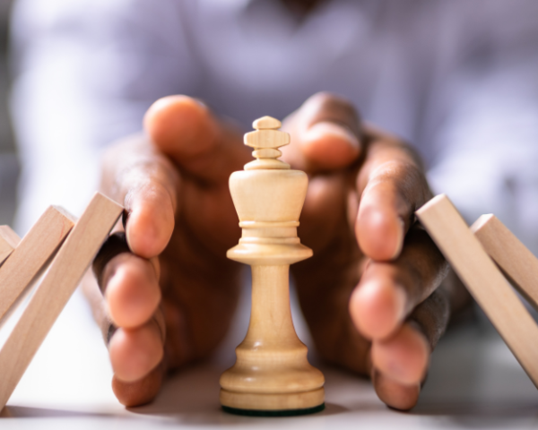 A person stabilizing falling blocks with a chess piece, symbolizing risk and quality management training for projects and operations, focusing on quality management workshop and project management training by FutureForward